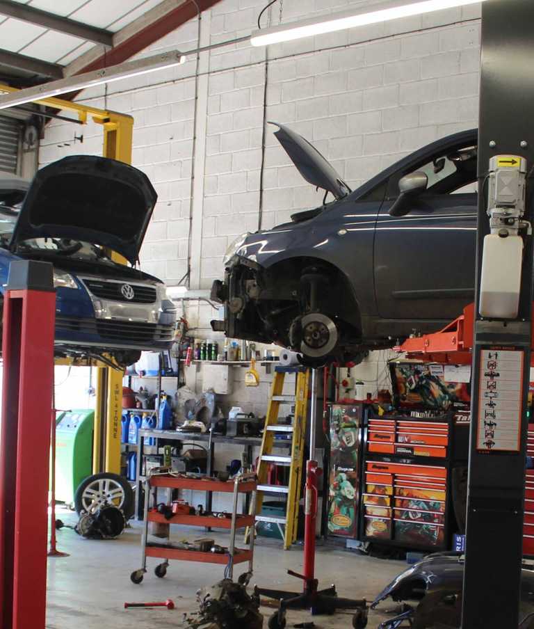 A car suspended in the air with a mechanic ready to work on it